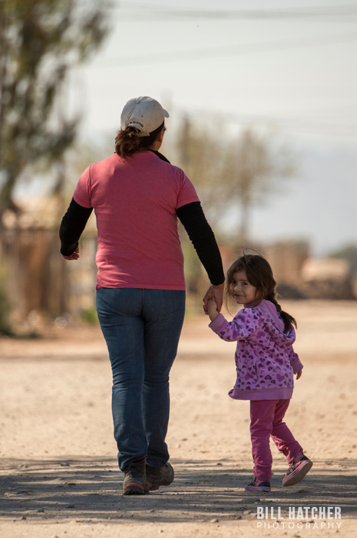 Photo by Bill Hatcher (Instagram: @bhatcherphoto). mother and her daughter take a walk in their hometown near the border. 