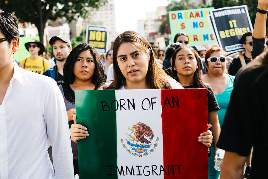 Woman holds Mexican flag that says "born of an immigrant."